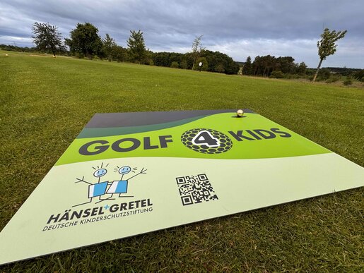 Ein Banner mit der Aufschrift "Golf4Kids" liegt auf einer grünen Rasenfläche