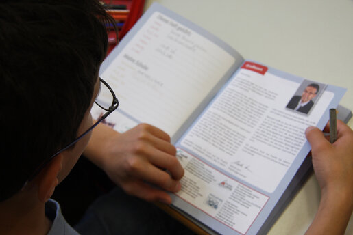 Ein Schüler liest sich aufmerksam das Hausaufgabenheft durch